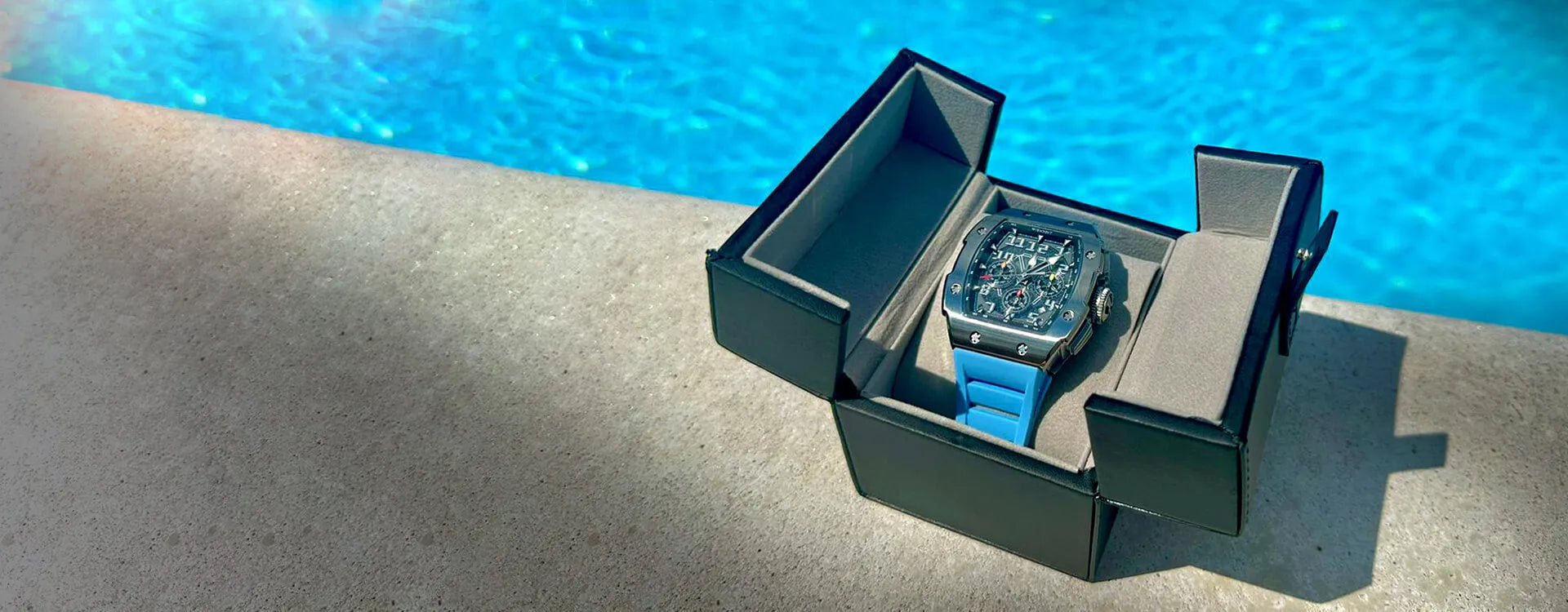 Luxury blue watch for men in an elegant box by a poolside.