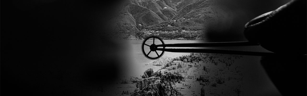 A watch gear held by tweezers against a mountainous landscape.